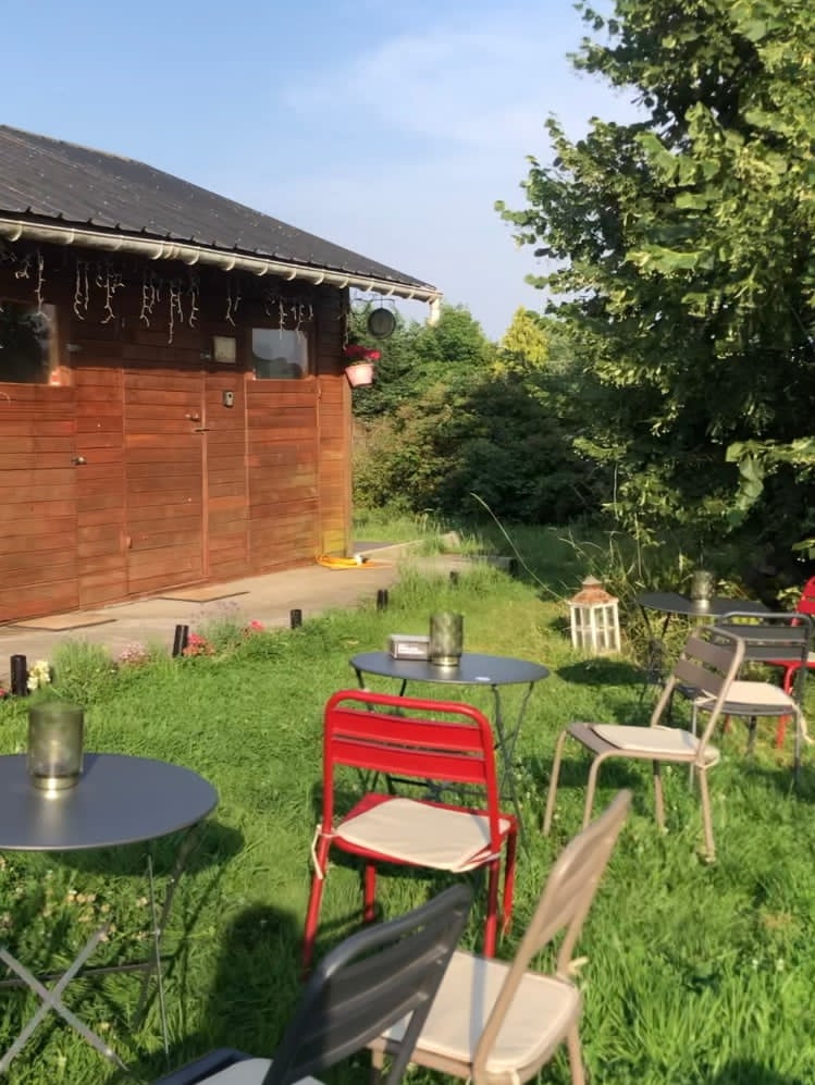 Espace extérieur de La vie est belle avec tables et chaises dans un jardin verdoyant